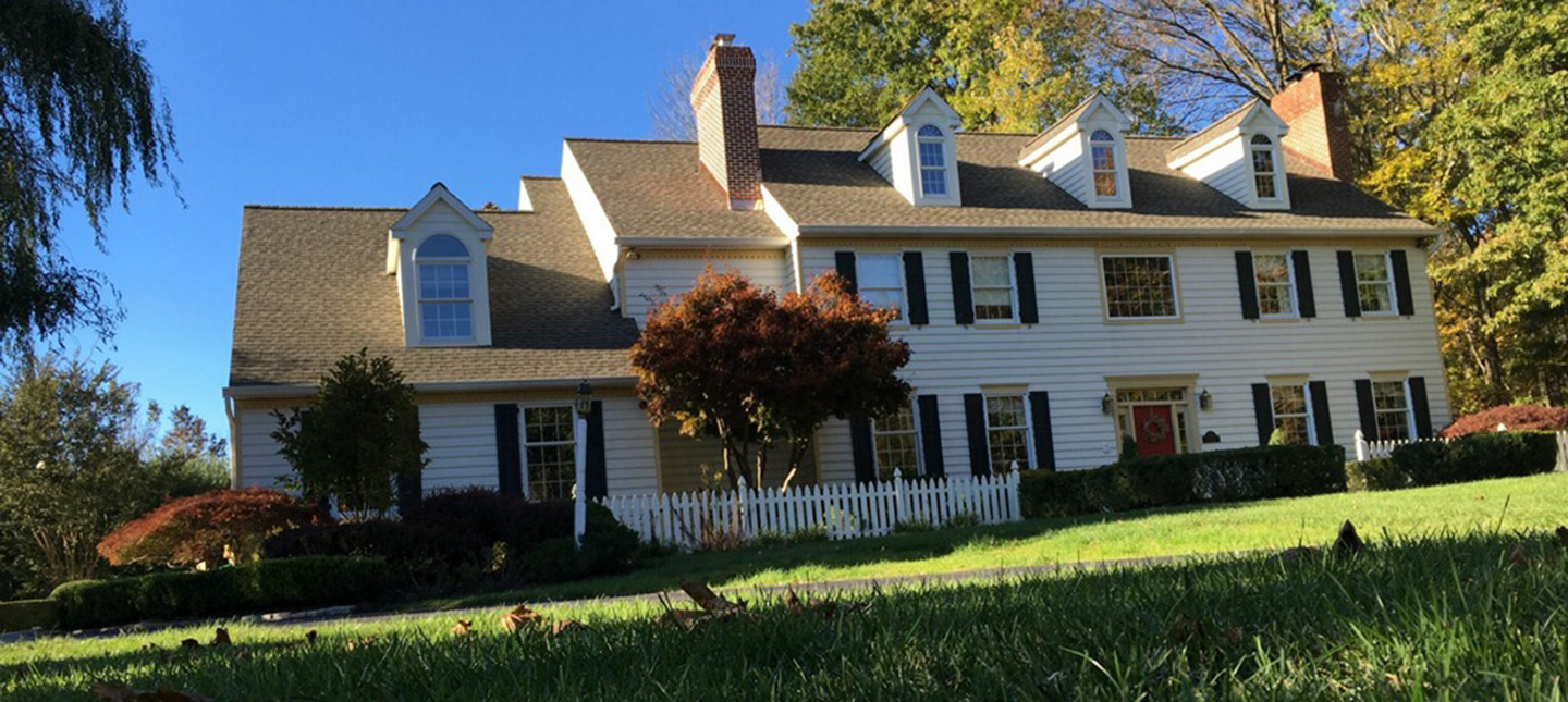 residential asphalt roofing project with brown shingles on large white home